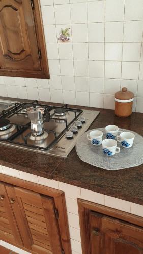 a kitchen counter with three cups and a stove at La piccola grande casetta Titina in Ischia
