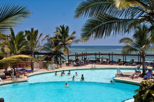 a swimming pool with several people in it at Leopard Beach Resort and Spa in Diani Beach