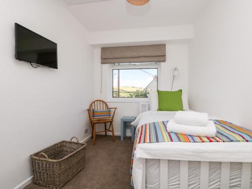 a small bedroom with a bed and a television at Rock Pool House in Helston