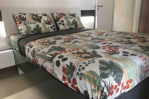 - un lit avec une couette et des oreillers colorés dans l'établissement Les terrasses du port, à Canet