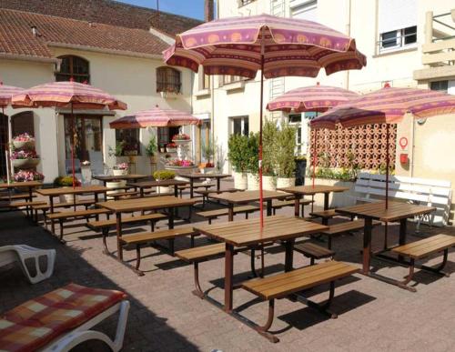 um grupo de mesas de piquenique com guarda-sóis num pátio em AUBERGE RIVA BELLA em Le Touquet-Paris-Plage