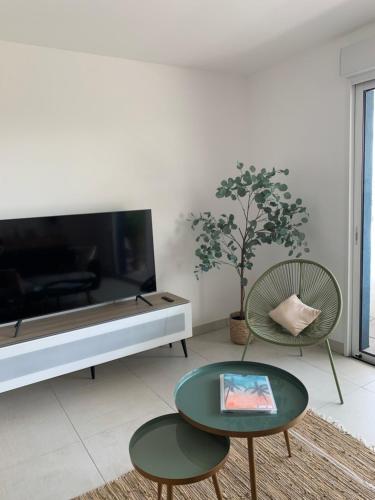 a living room with a tv and a table and chairs at Les terrasses du port in Canet-en-Roussillon