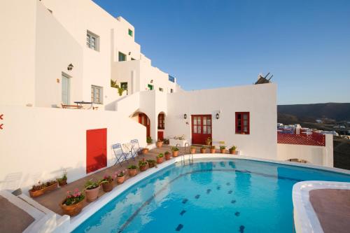 a swimming pool in front of a white building at Arhitektoniki Studios in Astypalaia