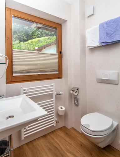 a bathroom with a toilet and a sink and a window at Landhaus Tipotsch in Schwendau
