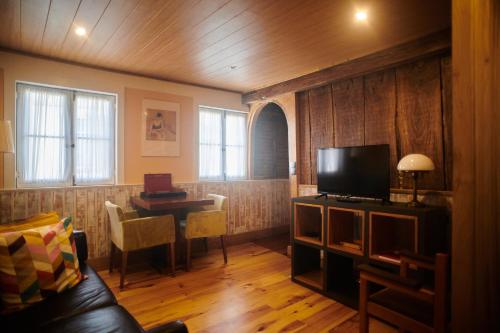 a living room with a couch and a television and a table at Casa da Praça Velha Guest House in Braga