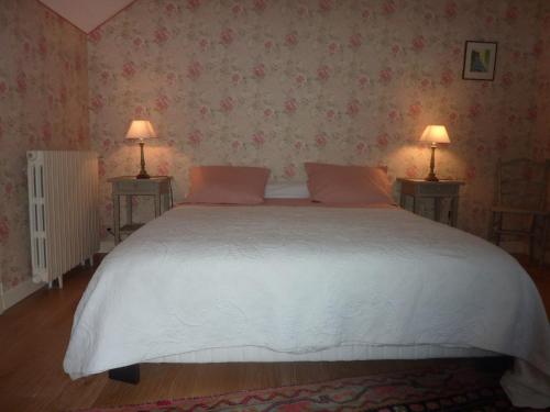 Luzech的住宿－L'orée du bois，一间卧室配有一张带两盏灯的大型白色床。