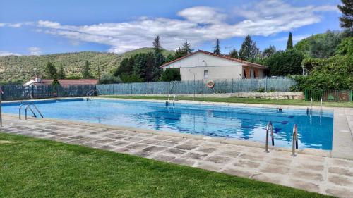 a large swimming pool in a yard with a fence at S&H El Caprichoso in Valdemaqueda