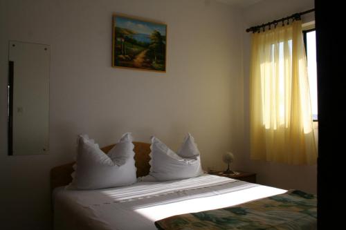 a bedroom with a bed with white pillows and a window at Apartment Sevid in Sevid