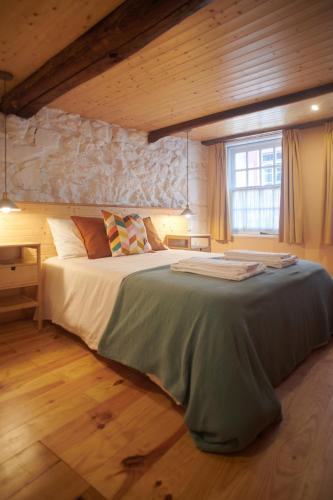a bedroom with a large bed with a stone wall at Casa da Praça Velha Guest House in Braga