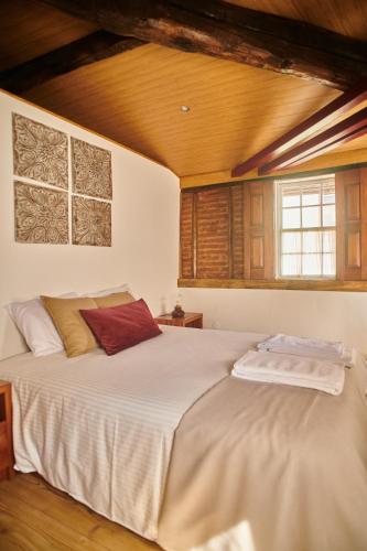 a bedroom with a large white bed with a wooden ceiling at Casa da Praça Velha Guest House in Braga