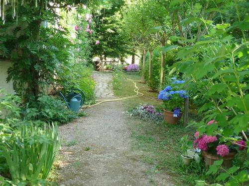 un jardin avec un chemin planté de fleurs et de plantes dans l'établissement L'orée du bois, à Luzech