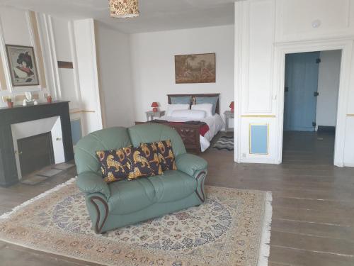 - un salon avec un canapé vert et un lit dans l'établissement Le Chateau, à Châteauponsac