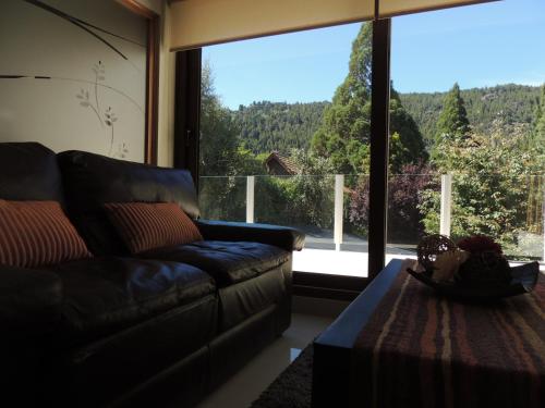 a living room with a couch and a large window at Abedul Apartamentos in San Martín de los Andes