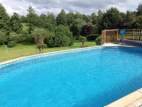 a large blue swimming pool in a yard at La Gasteboisiere with swimming pool and games room in Le Mesnil-Adelée