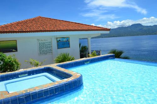 a swimming pool in front of a house with a body of water at Eden Resort in Santander