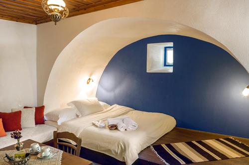 a bedroom with a large bed with a blue wall at Saxonis Houses & Saxonis Villa in Papigko