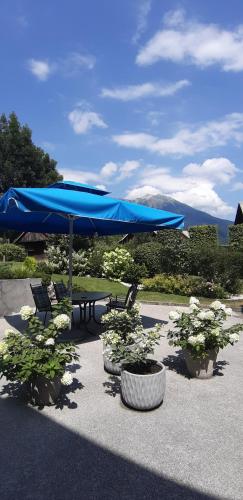 a blue umbrella and chairs and a table with flowers at Apartments Vesna in Bled