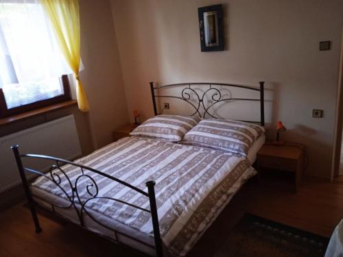 een slaapkamer met een zwart bed met kussens en een raam bij Apartmán Rózsika in Veľký Meder