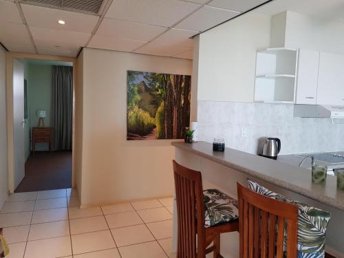 a kitchen with two chairs and a counter with a painting on the wall at Fabulous Ocean View Apartment in Secure Resort, 5 min Walk to Beaches & Restaurants in Willemstad