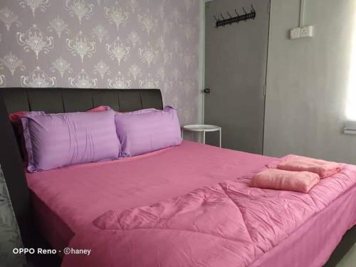 - un lit rose avec des oreillers violets dans une chambre dans l'établissement Haney Twin Homestay, à Jertih