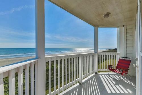 a porch with a red chair on the beach at Seascape 1111 condo in Galveston