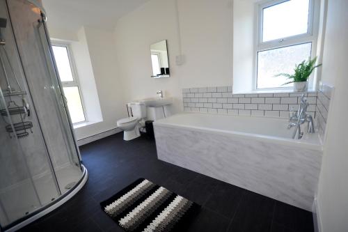 a white bathroom with a tub and a toilet at Heritage Holiday Accommodation in Pembrokeshire