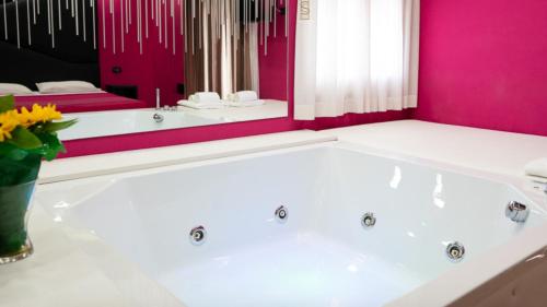 a bath tub in a bathroom with a pink wall at Sweet Central Hotel in Caserta