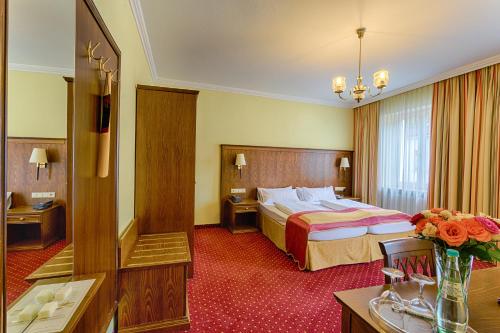 バーデン・バーデンにあるホテル レーマーホフのベッドとテーブルが備わるホテルルームです。