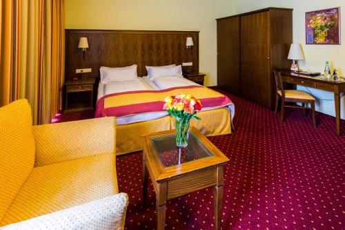 a hotel room with a bed and a vase of flowers on a table at Hotel Römerhof in Baden-Baden