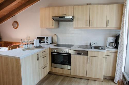 a kitchen with wooden cabinets and a stove top oven at Ferienwohnungen Haid in Schönau am Königssee