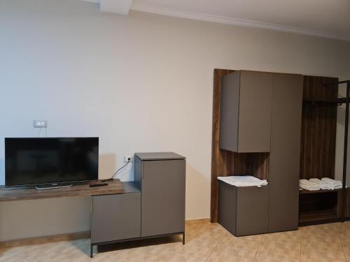 um quarto com uma secretária, uma televisão e um armário em Regina Garden Vlore em Vlorë