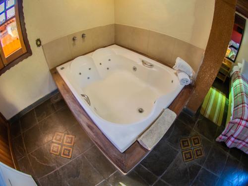 a large bath tub in a bathroom with a floor at Villa da Vila in Monte Verde