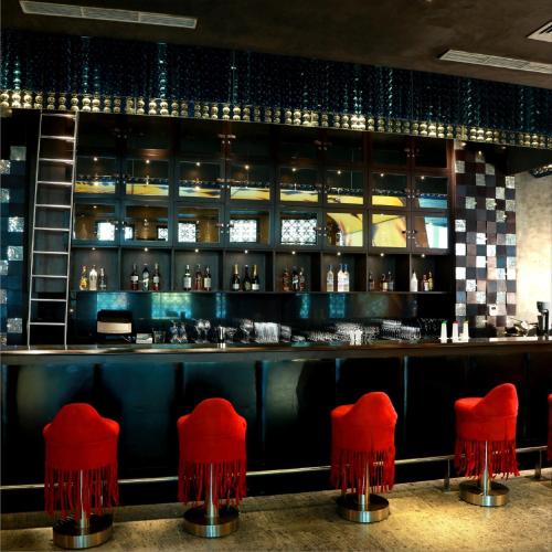 a bar with red stools in a restaurant at Radisson Blu Hotel MBD Ludhiana in Ludhiana