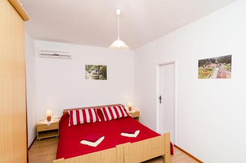 a white bedroom with a red bed with red sheets at Guest House Kola in Slano