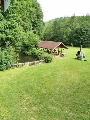 a picnic shelter in a field next to a river at Fontana erdélyi vendégház in Odorheiu Secuiesc