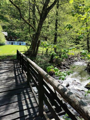 a wooden bridge over a river with a house in the background at Fontana erdélyi vendégház in Odorheiu Secuiesc