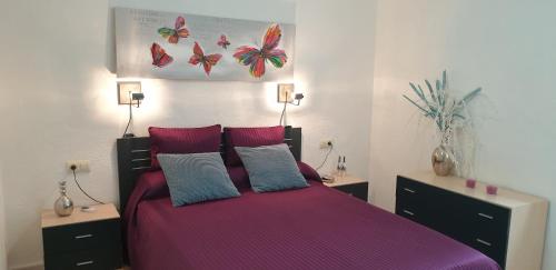 - une chambre dotée d'un grand lit avec des draps et des oreillers violets dans l'établissement EL Gecko, à Alcossebre