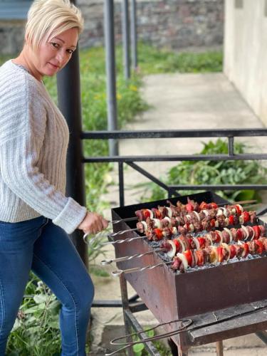 a woman is cooking food on a grill at Hotel Elegant in Stepantsminda