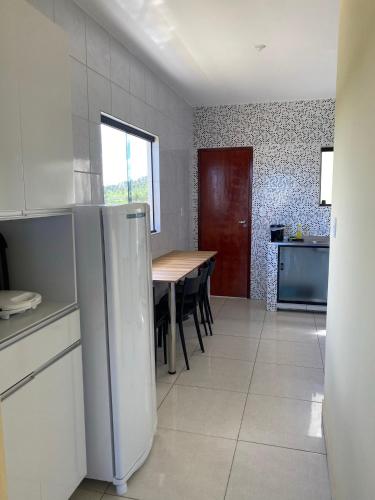 a kitchen with a table and a refrigerator in it at Mellim Residence in Maragogi