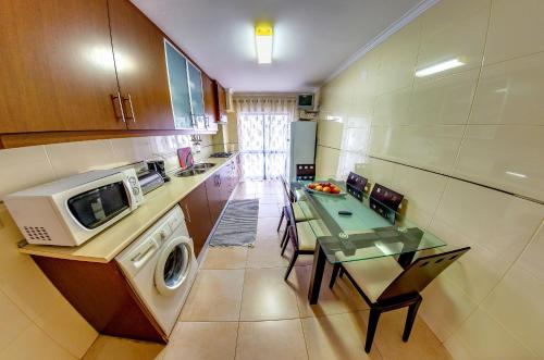 a kitchen with a washer and a table and a microwave at Apartamentos 7 Saias - Centro in Nazaré