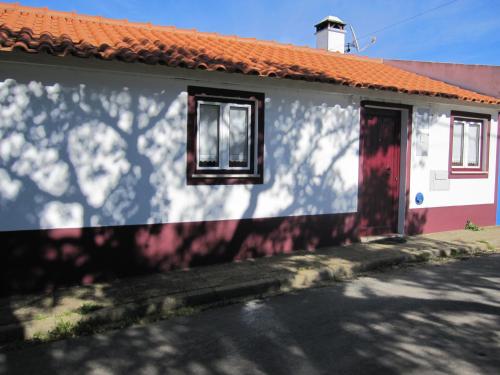 a white house with an orange roof and a red door at Casa Alentejana in São Teotónio