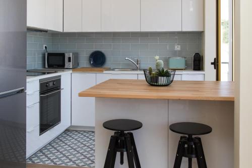 a kitchen with white cabinets and black stools at Templar Spot in Tomar