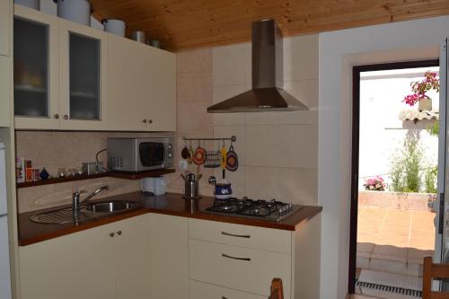 a kitchen with a sink and a stove top oven at Casa Alentejana in São Teotónio