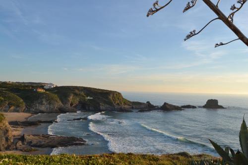 a view of a beach with rocks and the ocean at Casa Alentejana in São Teotónio