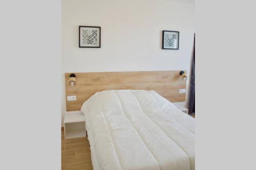 1 cama blanca en un dormitorio con 2 cuadros en la pared en Superbe studio idéalement situé ! en Avoine