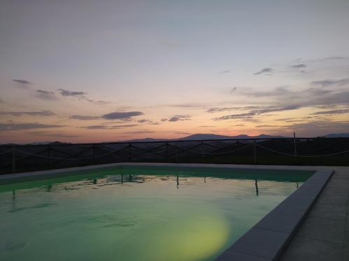 a swimming pool with a sunset in the background at Country House Ca'Balsomino in Urbino