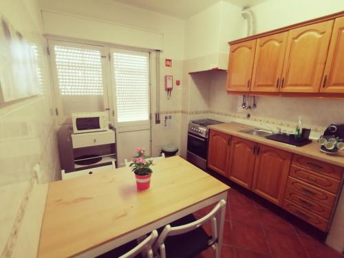 una cocina con armarios de madera y una mesa con flores. en Apartamento S. Luis, en Faro