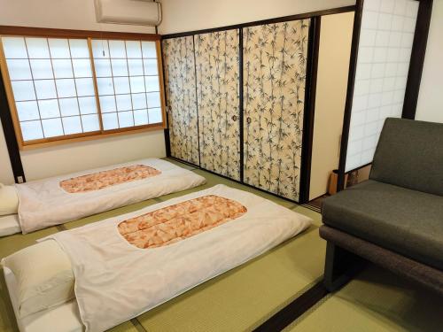 twee bedden in een kamer met een stoel bij Kyoto Villa Fuka in Kyoto