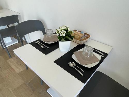 a white table with two plates and a vase of flowers at Nature Room in Olbia