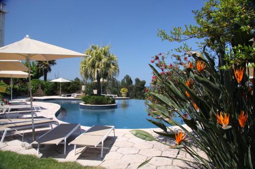 a pool with chairs and umbrellas in a resort at La Solenzara hôtel - 3 Etoiles Supérieur - Appartement & SPA in Sari Solenzara